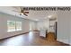 Open-concept living space featuring wood floors, large windows, and a kitchen with white cabinets at 601 Queens Rd, Gastonia, NC 28052