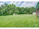 Expansive backyard featuring a lush green lawn, mature trees, and storage sheds at 6573 Weldon Nw Cir # 22, Concord, NC 28027
