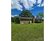 Rear view of brick home featuring an expansive backyard with lush lawn and mature trees at 6573 Weldon Nw Cir # 22, Concord, NC 28027