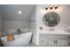 Bright bathroom featuring a soaking tub, a marble top vanity, round mirror, and modern fixtures at 7455 Ivey Dr, Sherrills Ford, NC 28673