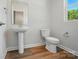 Bathroom features a pedestal sink, toilet and a window for natural light at 908 Westminster Dr, Statesville, NC 28677