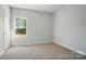 Bright bedroom with neutral carpet, window with wooded view, and a white door at 908 Westminster Dr, Statesville, NC 28677