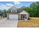 Charming two-story home featuring a gray exterior, stone accents, and a spacious two-car garage at 908 Westminster Dr, Statesville, NC 28677
