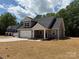 Gray vinyl sided new construction home with a two-car garage, rock accents and freshly seeded yard at 908 Westminster Dr, Statesville, NC 28677