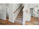 Carpeted staircase with wood handrail leading to upper level near an open area and modern luxury vinyl plank flooring at 908 Westminster Dr, Statesville, NC 28677