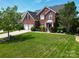 A stately brick home boasts a lush lawn, mature trees, and a welcoming front entrance at 9612 Indian Beech Nw Ave # 1266, Concord, NC 28027
