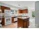 Kitchen featuring white appliances, wood cabinets, a kitchen island, and a dining area at 9927 Raddington Ln, Charlotte, NC 28269