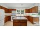 Kitchen featuring white appliances, wood cabinets, a kitchen island, and a window above the sink at 9927 Raddington Ln, Charlotte, NC 28269