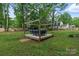 Secluded backyard area with a wooden deck and pergola over comfortable seating surrounded by mature trees at 1014 Vandalia Dr, Charlotte, NC 28212