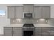 A stylish kitchen featuring gray cabinets, stainless steel appliances, and modern backsplash at 14028 Parkside Crossing Dr # 331, Charlotte, NC 28273