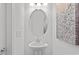 Half-bathroom with pedestal sink, oval mirror, decorative lighting, and artwork at 15926 Parkside Crossing Dr # 322, Charlotte, NC 28273