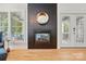 Modern fireplace with a black tile surround, a round mirror, and hardwood floors at 201 Mills Ln, Fort Mill, SC 29708