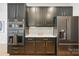 Kitchen featuring built-in appliances, black cabinetry, and stylish backsplash at 201 Mills Ln, Fort Mill, SC 29708