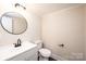 Bathroom featuring a modern round mirror, vanity, and toilet at 210 W 15Th St, Newton, NC 28658