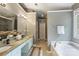 Bright bathroom featuring a double vanity with granite countertop, soaking tub, and glass-enclosed shower at 2100 Sablewood Dr, Charlotte, NC 28205