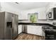 Cozy kitchen with white cabinets, stainless steel appliances, a window, and black countertops at 2109 Brewton Dr, Charlotte, NC 28206