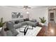 Stylish living room with a modern gray sofa, patterned rug, sleek glass table, and hardwood floors at 2109 Brewton Dr, Charlotte, NC 28206