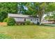 Charming single-story home with a lush green lawn, mature landscaping, and a quaint front porch at 21614 Colina Dr, Cornelius, NC 28031