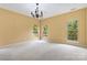 Bright bedroom with neutral walls, carpet, large windows offering scenic views, and a classic chandelier at 2346 Donnington Nw Ln, Concord, NC 28027