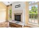 Close-up of the fireplace with stone hearth, white mantel, and large windows offering views of the backyard at 2346 Donnington Nw Ln, Concord, NC 28027