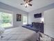 Comfortable bedroom with a dark dresser, TV, ceiling fan, two windows, and a light gray accent wall at 2608 Henry Baucom Rd, Monroe, NC 28110
