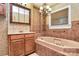 Bathroom with brown tiling, vanity, jacuzzi tub, chandelier, and brown tiling at 261 Melrose Sw Dr, Concord, NC 28025