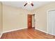 An empty bedroom with wood floors, a ceiling fan, an open wooden door, and a closed closet door at 261 Melrose Sw Dr, Concord, NC 28025
