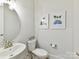 Nicely decorated half bathroom with a sink, toilet and paintings with a beach theme at 3135 Everly Enclave Way, Charlotte, NC 28210