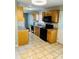 Efficient kitchen with light wood cabinetry, tile floors, and modern black appliances at 3701 Tipperary Pl, Charlotte, NC 28215