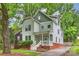 Charming two-story home featuring a covered front porch, complemented by a well-maintained lawn and mature trees at 409 W Kingston Ave, Charlotte, NC 28203