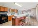 Open kitchen featuring wooden cabinets, black appliances, a breakfast bar, and an adjacent dining area at 4122 Canal Rd, Marshville, NC 28103