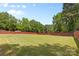 Spacious backyard featuring a large grassy area, surrounded by mature trees and a red fence at 4600 Beatties Ford Rd, Charlotte, NC 28216