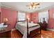 This bedroom features a four poster bed, ceiling fan, a wooden dresser and matching furnishings and bright red wall paper at 4600 Beatties Ford Rd, Charlotte, NC 28216