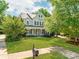 Inviting two-story home with a lush green lawn, mature trees, and a charming front porch at 533 Montgrove Nw Pl, Concord, NC 28027