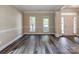 Open-concept living room with gray wood flooring and a view of the front yard through large windows at 533 Montgrove Nw Pl, Concord, NC 28027