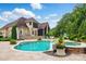 Expansive backyard showcasing pool, hot tub, stone patio, and lush landscaping of this home's exterior at 581 Medora Ln, Fort Mill, SC 29708