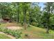 A peaceful backyard with mature trees, landscaping, and a charming outbuilding providing a private retreat at 603 Sunnybrook Dr, Monroe, NC 28110