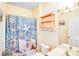 Cozy bathroom featuring a patterned shower curtain, white fixtures, and a wooden shelf at 6227 Castlecove Rd, Charlotte, NC 28278