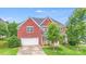 Traditional brick home featuring an attached two-car garage, lush green lawn, and mature trees at 6227 Castlecove Rd, Charlotte, NC 28278