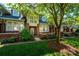 Charming brick townhome featuring lush landscaping, a covered front porch, and a well-manicured lawn at 6312 Mission Pl, Charlotte, NC 28210