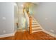 Bright foyer with hardwood floors, a staircase with white railing, and a door to the outside at 6312 Mission Pl, Charlotte, NC 28210