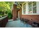 Inviting covered front porch with brick columns, a cozy seating area, and a view of the landscaped yard at 6312 Mission Pl, Charlotte, NC 28210