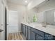 Bathroom featuring a double sink vanity with gray cabinets, white countertop, large mirror, wood-look floors, and ample lighting at 910 Westminster Dr, Statesville, NC 28677