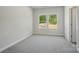 Bright bedroom featuring gray carpet, neutral walls, two double-hung windows overlooking the landscape, and white trim at 910 Westminster Dr, Statesville, NC 28677