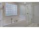 Bright bathroom featuring a soaking tub, glass-enclosed shower, and privacy window at 1069 Sedgefield Rd, Charlotte, NC 28209