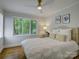 Cozy bedroom with hardwood floors and a large window overlooking mature landscaping at 1069 Sedgefield Rd, Charlotte, NC 28209