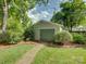 View of detached garage with stone path and green doors surrounded by lush greenery at 1069 Sedgefield Rd, Charlotte, NC 28209
