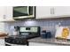 Close-up of modern kitchen with stainless steel appliances, granite countertops, and a stylish backsplash at 123 Rustling Waters Dr, Mooresville, NC 28117