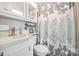 Functional bathroom with a vanity, toilet, and shower with a patterned curtain at 125 Maple St, New London, NC 28127
