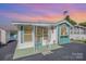 Charming home with teal and white exterior, decorative accents, and delightful curb appeal under a colorful sunset sky at 125 Maple St, New London, NC 28127